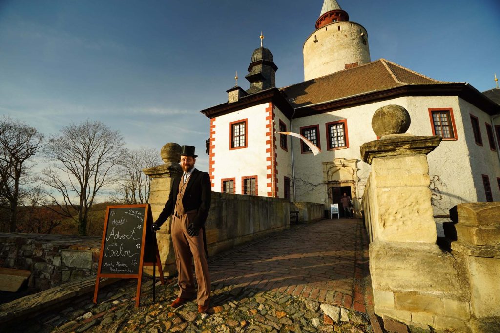 Mann in historischem Frack steht vor der Burg Posterstein