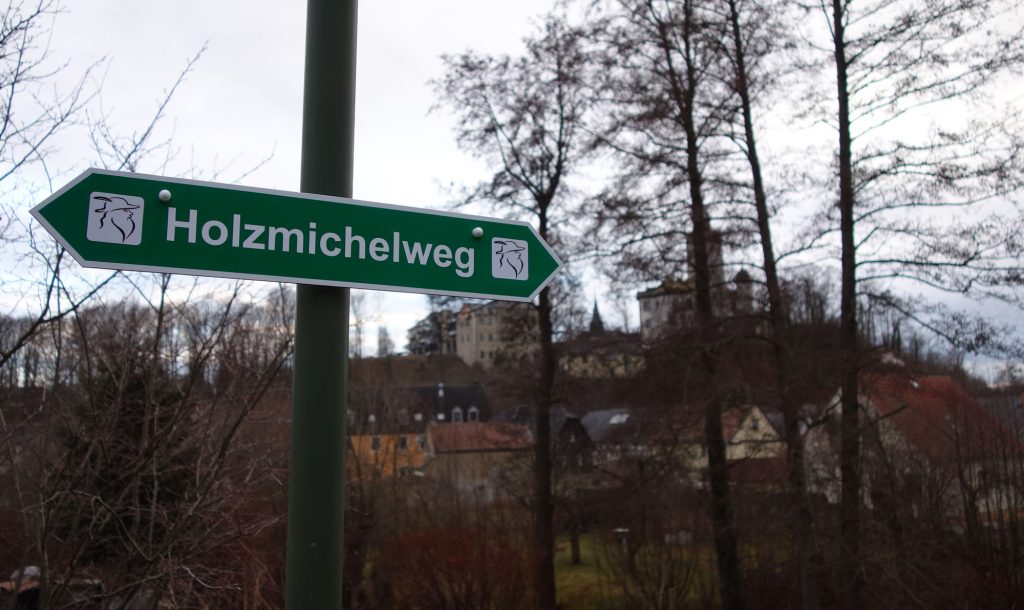 Schild "Holzmichelweg", im Hintergrund die Burg Posterstein.