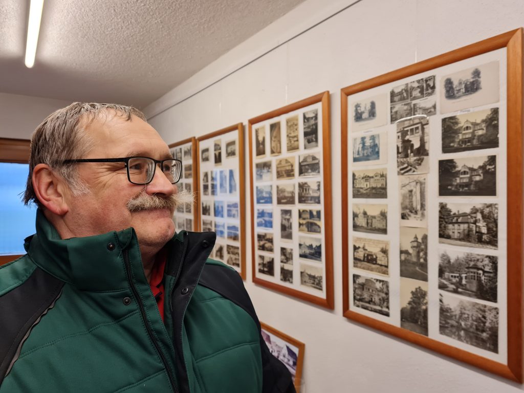 Postkarten-Sammler Frank Erler vor Bilderrahmen mit Ansichtskarten aus seiner Sammlung